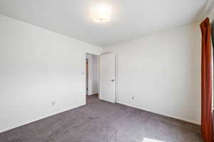 Carpeted empty room featuring baseboards