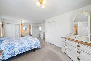 Bedroom featuring light colored carpet and two closets