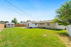 Rear view of house featuring a fenced backyard, an outdoor structure, and a patio