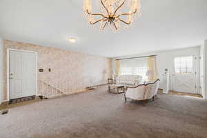 Living area with wallpapered walls, carpet floors, and a chandelier