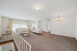 Carpeted living area with a chandelier and baseboards