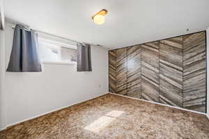 Unfurnished bedroom with carpet flooring and wooden walls