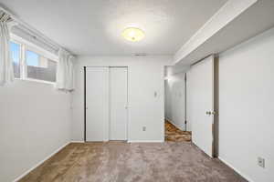 Unfurnished bedroom with a textured ceiling, carpet, and a closet