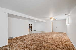 Carpeted spare room with a ceiling fan and baseboards