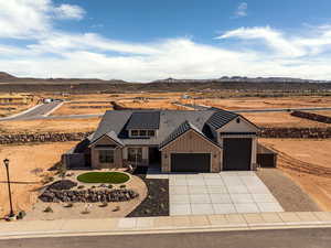 Modern inspired farmhouse with stone siding, solar panels, board and batten siding, a garage, and concrete driveway