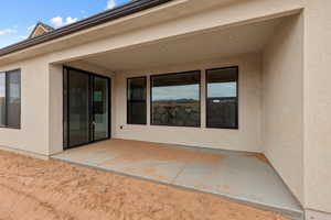 Back of house with stucco siding and a patio