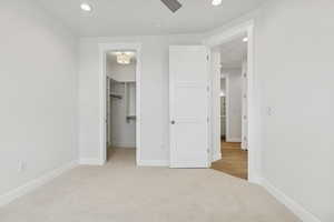 Unfurnished bedroom featuring carpet floors, recessed lighting, a spacious closet, and a ceiling fan