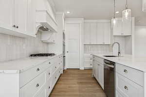 Kitchen featuring light wood-style floors, stainless steel dishwasher, backsplash, white cabinetry, and recessed lighting