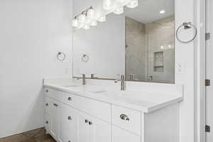 Bathroom with double vanity, a marble finish shower, and recessed lighting