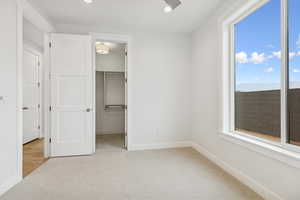 Unfurnished bedroom featuring light colored carpet, a spacious closet, and recessed lighting