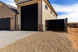 View of property exterior featuring brick siding, board and batten siding, driveway, and a gate