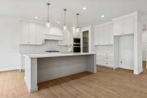 Kitchen with decorative backsplash, white cabinets, light wood-style flooring, and recessed lighting