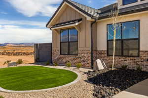 View of property exterior featuring board and batten siding, brick siding, a lawn, and a mountain view