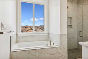 Bathroom featuring a bath and a marble finish shower