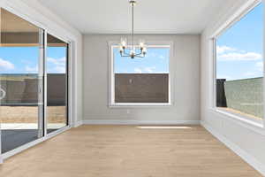 Unfurnished dining area featuring light wood finished floors and a chandelier