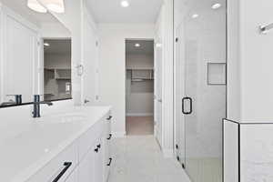 Full bathroom with marble look tiles, a marble finish shower, vanity, a walk in closet, and recessed lighting