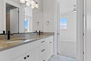 Bathroom featuring double vanity, marble look tiles, and ceiling fan