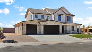 View of front of house featuring concrete driveway, stone siding, a garage, and board and batten siding