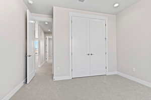 Unfurnished bedroom featuring recessed lighting, light colored carpet, and a closet
