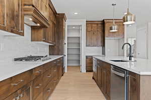 Kitchen with backsplash, recessed lighting, light wood-style floors, stainless steel appliances, and hanging light fixtures