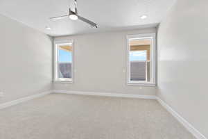 Unfurnished room featuring light colored carpet, healthy amount of natural light, a textured ceiling, a ceiling fan, and recessed lighting