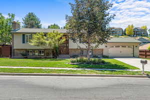 Split foyer home with driveway, an attached garage, a chimney, and brick siding