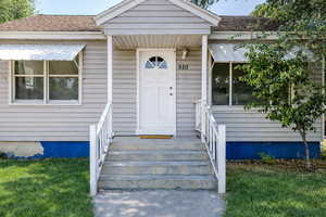 Property entrance with roof with shingles and a lawn
