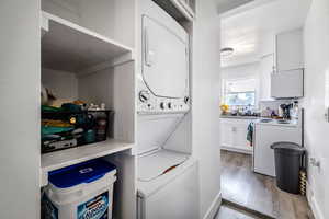 Laundry room featuring stacked washer / drying machine and light wood-style flooring