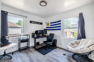 Office with wood finished floors and healthy amount of natural light