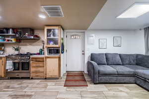 Kitchen featuring stainless steel appliances, open floor plan, light countertops, and wall chimney range hood