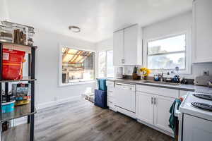 Kitchen featuring white appliances, dark wood-style flooring, white cabinetry, and dark countertops