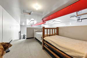 Bedroom featuring attic access and concrete floors
