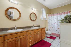 Bathroom featuring tile patterned flooring, double vanity, and a shower with curtain