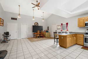 Kitchen with a peninsula, a ceiling fan, stainless steel appliances, a breakfast bar area, and light tile patterned floors