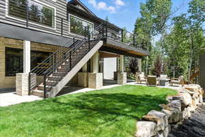 Back of property featuring stairs, a lawn, a patio, and a wooden deck