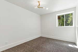 Empty room with dark colored carpet, a chandelier, and recessed lighting