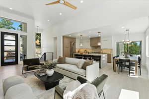 Living area featuring recessed lighting, light wood-type flooring, a chandelier, a towering ceiling, and a ceiling fan