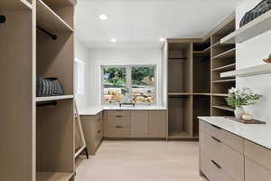 Walk in closet with light wood-style floors
