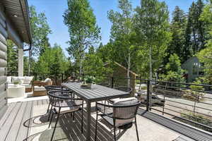 Wooden deck featuring view of wooded area and outdoor dining space