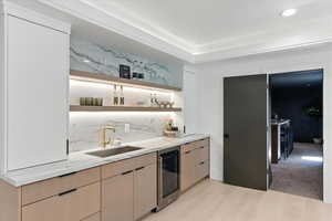 Bar area with light wood finished floors and wine cooler