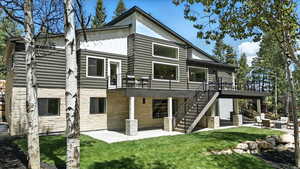 Back of property featuring a patio area, board and batten siding, stairs, and a lawn