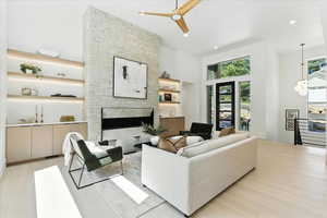 Living room with a stone fireplace, ceiling fan, recessed lighting, a high ceiling, and a chandelier