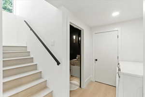Staircase featuring wood finished floors, separate washer and dryer, and recessed lighting