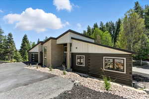 View of front of house featuring board and batten siding, log siding, and driveway