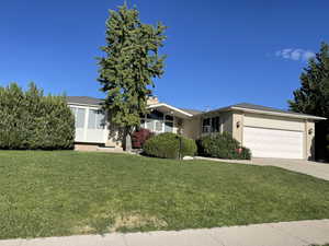 View of front of home featuring brick siding, an attached garage, a front yard, and concrete driveway
