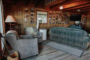Living area featuring wood walls, wood finished floors, and beam ceiling