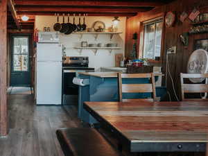 Dining room featuring wooden walls, beamed ceiling, wood finished floors, and stairway
