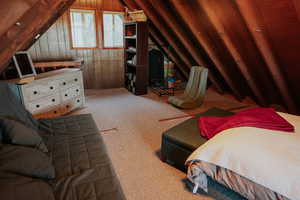 Carpeted bedroom with vaulted ceiling and wood walls