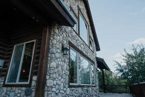 View of side of home featuring stone siding and a deck