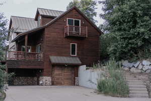 View of side of home featuring a garage, a metal roof, log veneer siding, concrete driveway, and a standing seam roof